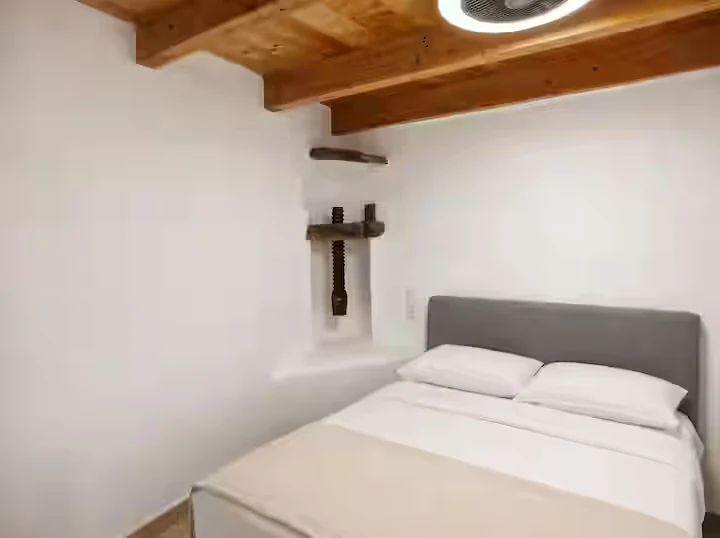 Bright queen bedroom with timber ceiling at Perliti