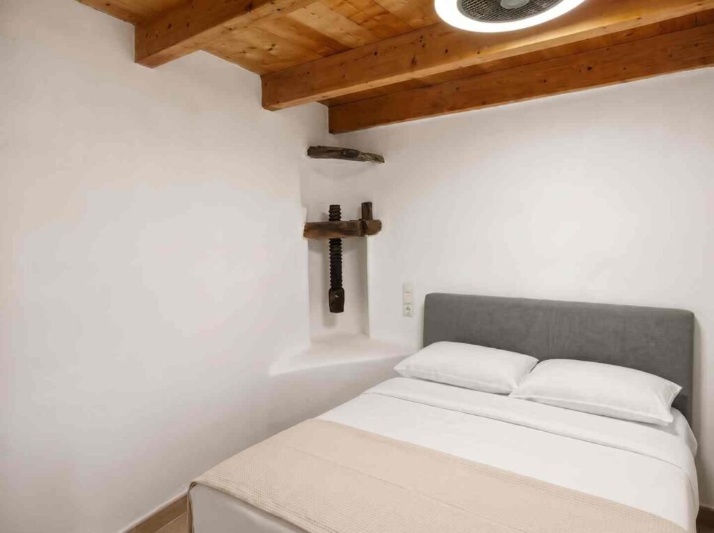 Queen bedroom with white linens and timber ceiling at Perliti Cycladic House